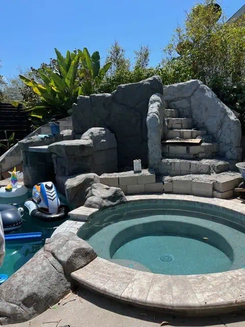 Outdoor stone staircase leading to a hot tub with natural rock accents.