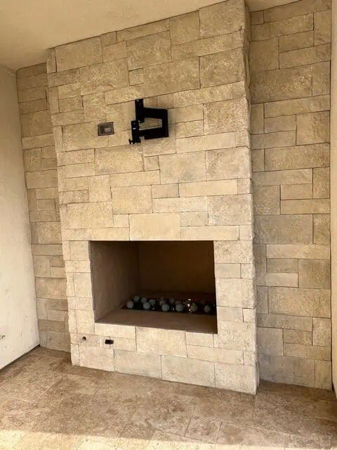 Fireplace with stone facade and sleek black wall-mounted fixture for a contemporary look.