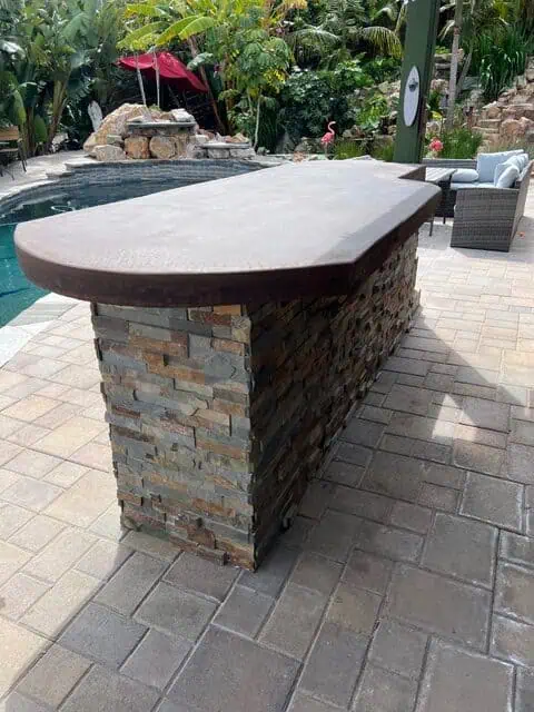 Durable stone and concrete outdoor bar with a sleek design, perfect for poolside gatherings and outd.