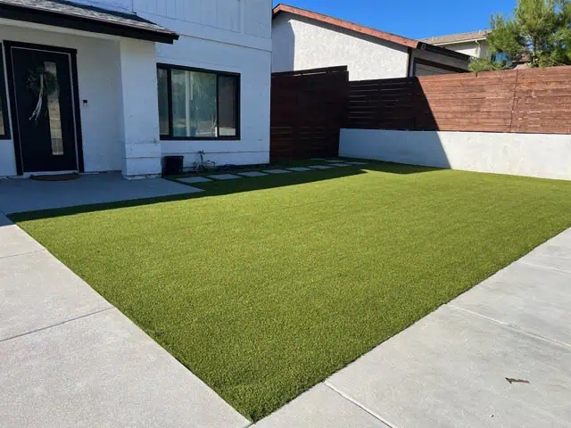 Artificial grass installation for a low-maintenance, attractive backyard landscape.