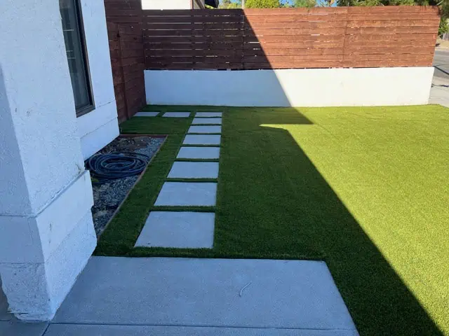 Backyard landscaping featuring concrete stepping stones and vibrant green grass for a stylish outdoo.