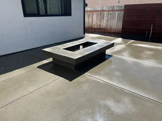Modern concrete patio with built-in fire pit in backyard.