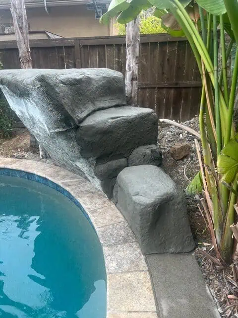 Custom rock waterfall feature by GFG Remodeling near pool area.