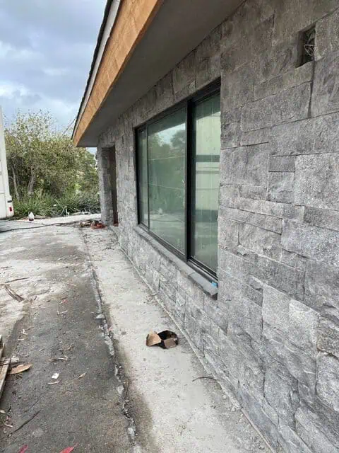 Stone exterior wall with large windows for a contemporary home.